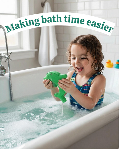 Child playing with a green dolphin-shaped bath bomb by Calla Lily Cosmetics + CL kids in a bubbly bathtub