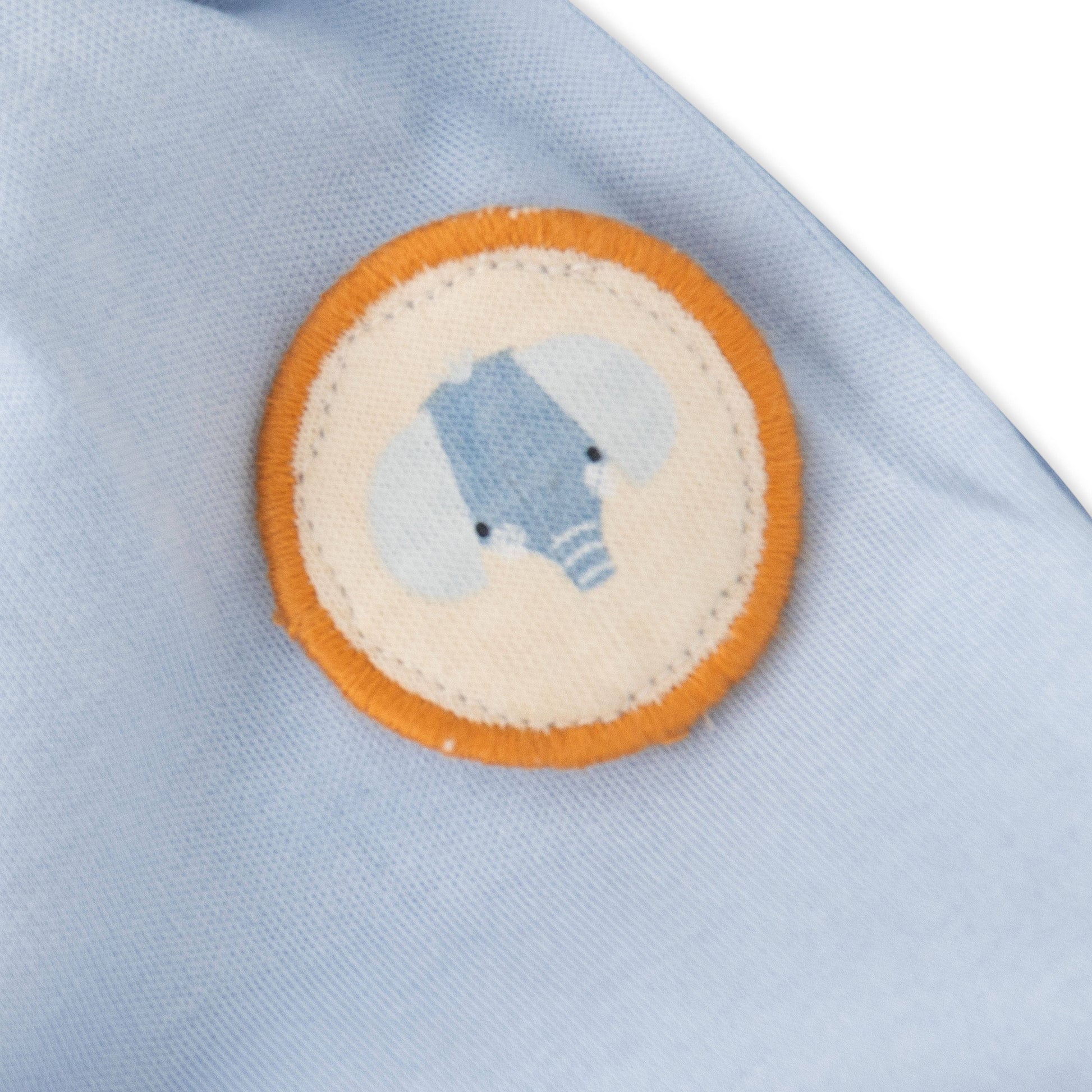 Close-up of a light blue fabric with a circular patch featuring a bear design.
