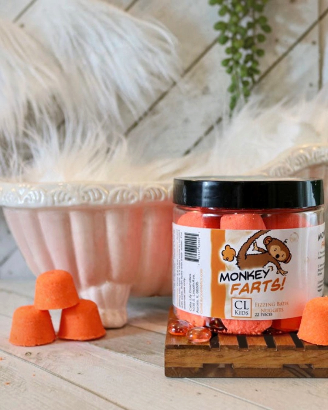 A container of gumdrop shaped orange "monkey farts" bath bombs with a tiny 3 bath bomb pyramid to its side
