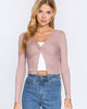 Woman wearing a pink long-sleeve top with a white underlayer and blue jeans on a white background