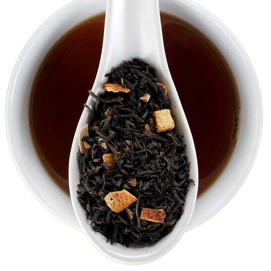 A white ceramic spoon filled with loose-leaf tea is centered over a white cup of dark brewed tea on a white background. The brand name 'Finest Elmwood County Inn' is printed in the top right corner.