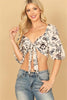 Woman wearing a floral top and jeans on a beige background