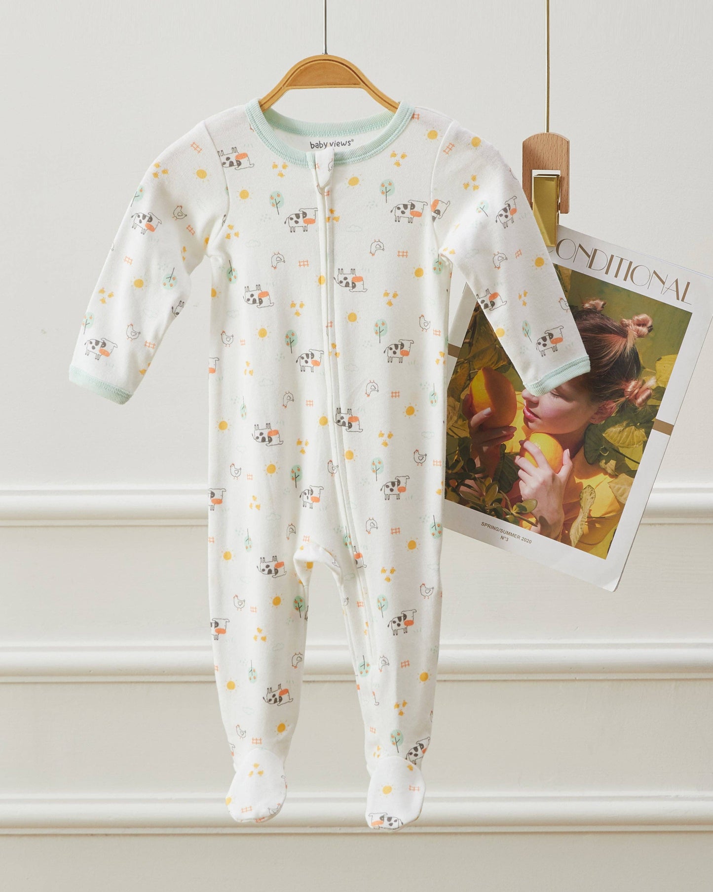 Baby onesie with floral pattern on a hanger against a white wall.