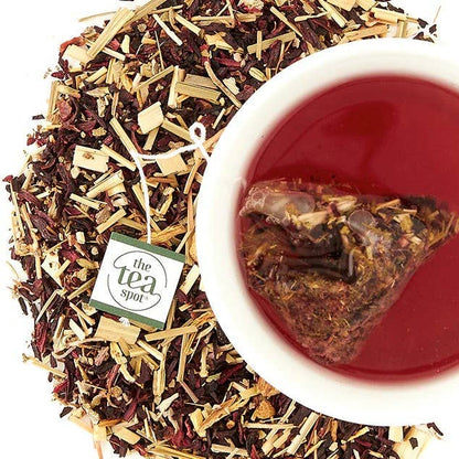 Tea leaves and a brewed tea in a cup with 'The Tea Spot' branding.