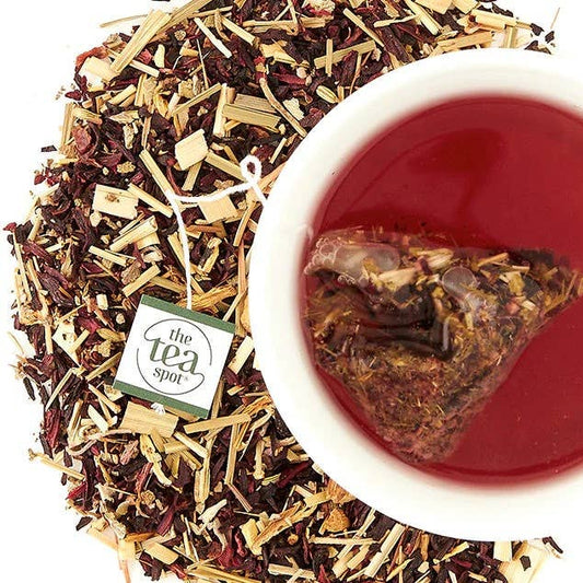 Tea leaves and a brewed tea in a cup with 'The Tea Spot' branding.