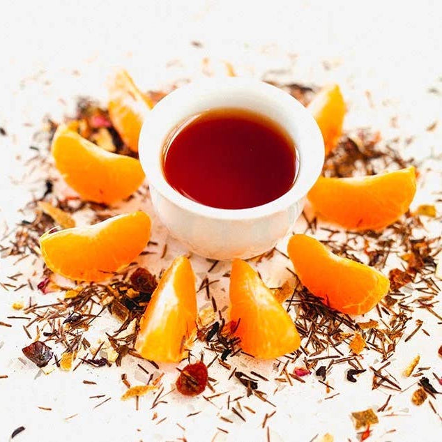 Tea cup with orange slices and dried herbs on a white background