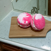 Two pink and white bunny tracks bath cookies on a wooden paddle