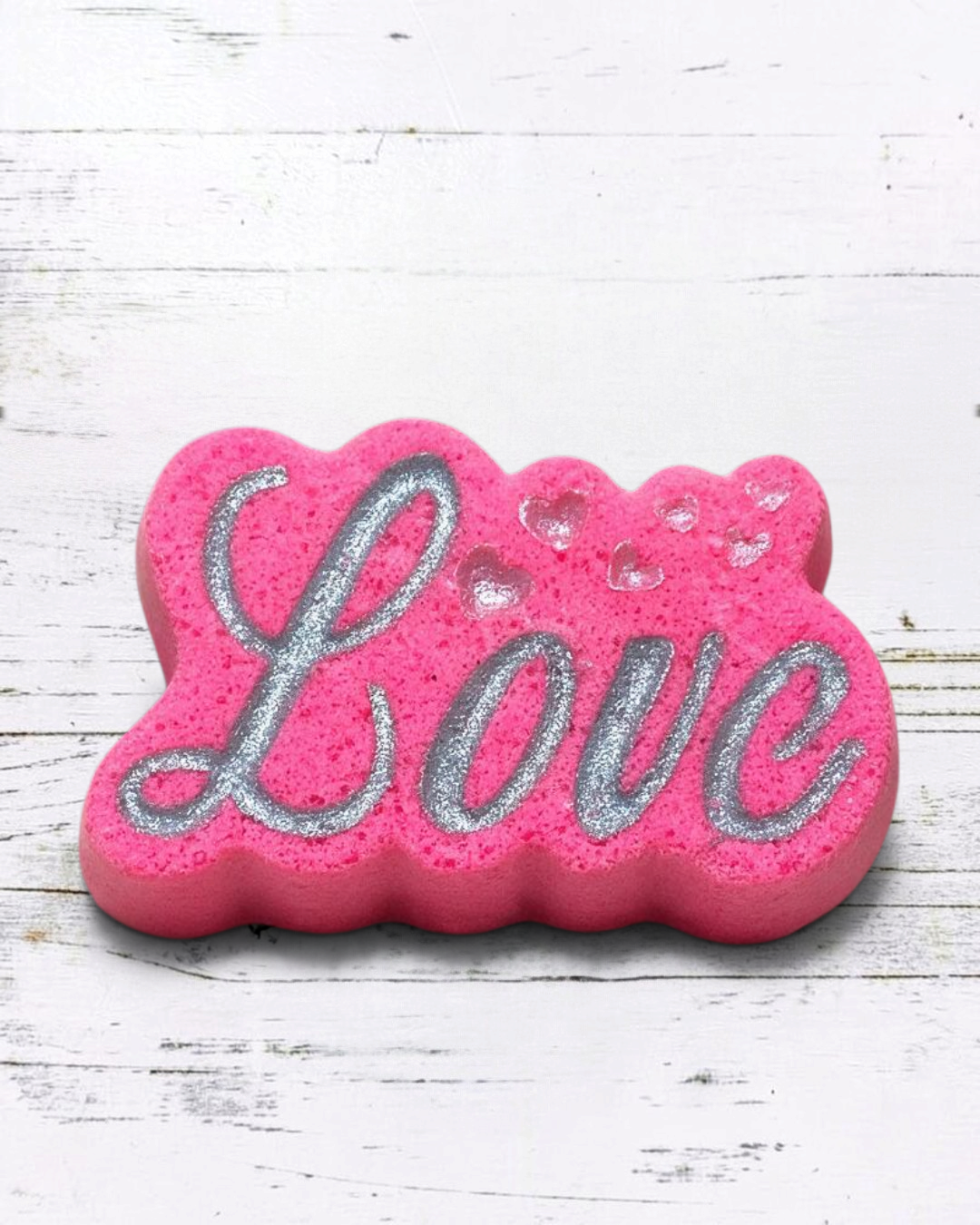 Calla Lily Cosmetics + CL kids pink Love bath bomb with silver glitter lettering and heart accents on a bathroom vanity