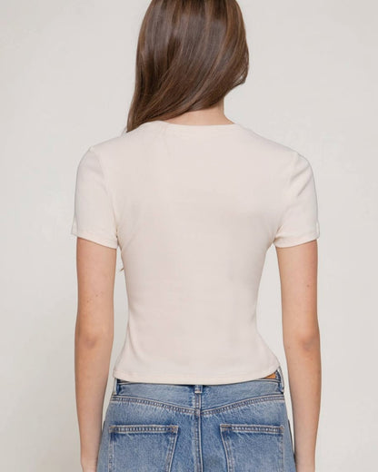 Person wearing a beige t-shirt and blue jeans against a plain background