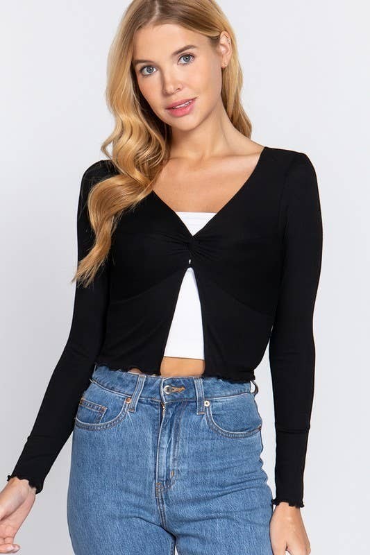Woman wearing a black long-sleeve top over a white crop top and blue jeans on a light gray background