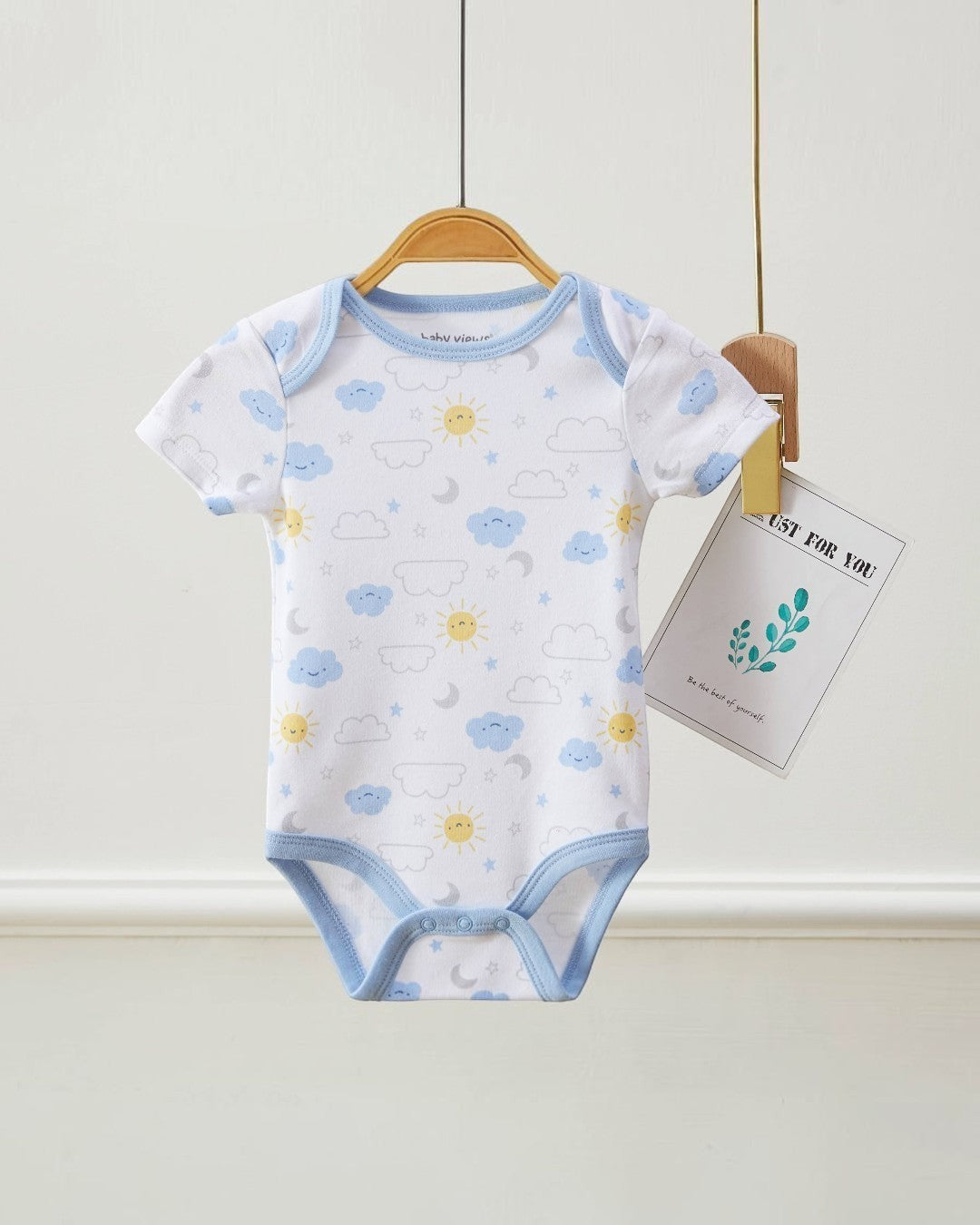 Baby bodysuit with cloud and flower pattern on a hanger