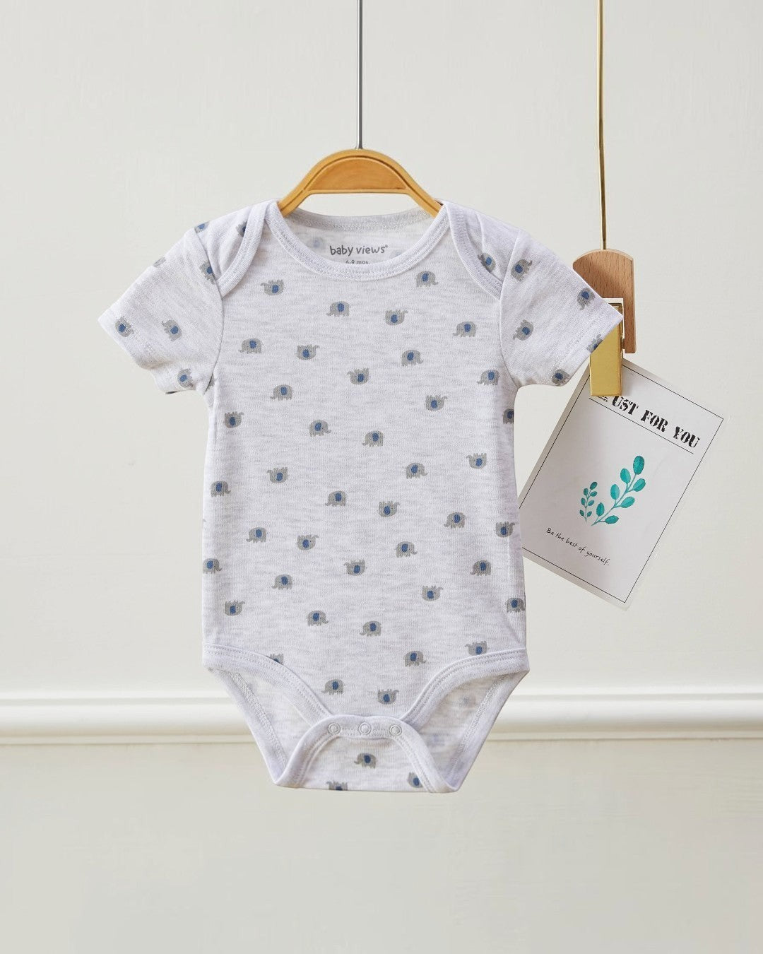 Gray baby onesie with blue patterns on a hanger against a white background