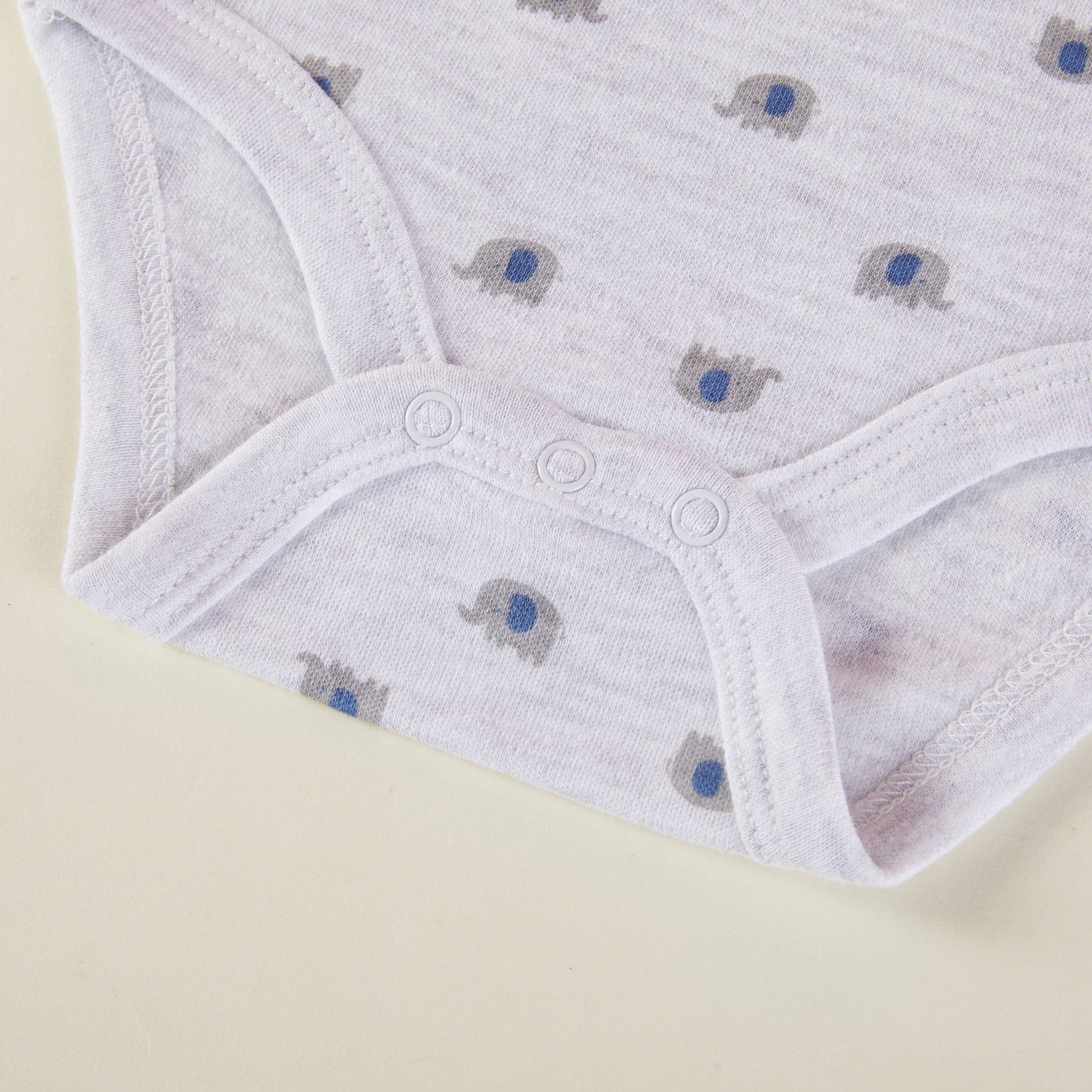 White baby pants with elephant pattern on a beige background