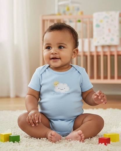 Baby sitting on a carpeted floor with colorful blocks, wearing a light blue onesie with a cloud design.