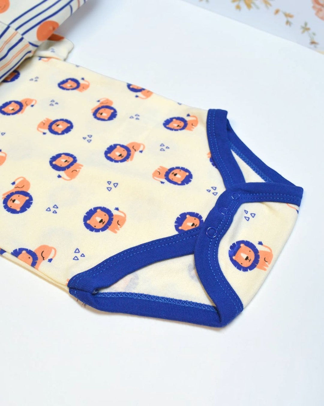 Baby onesie with lion pattern and blue trim on a white background
