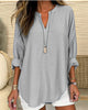 Woman wearing a gray oversized shirt with rolled-up sleeves and a necklace.
