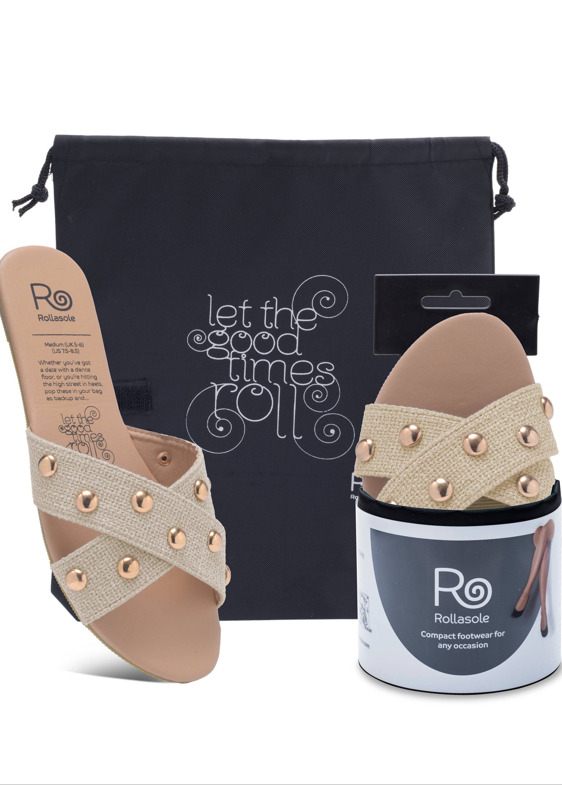 Pair of beige sandals with decorative straps, packaging, and a black bag on a white background.