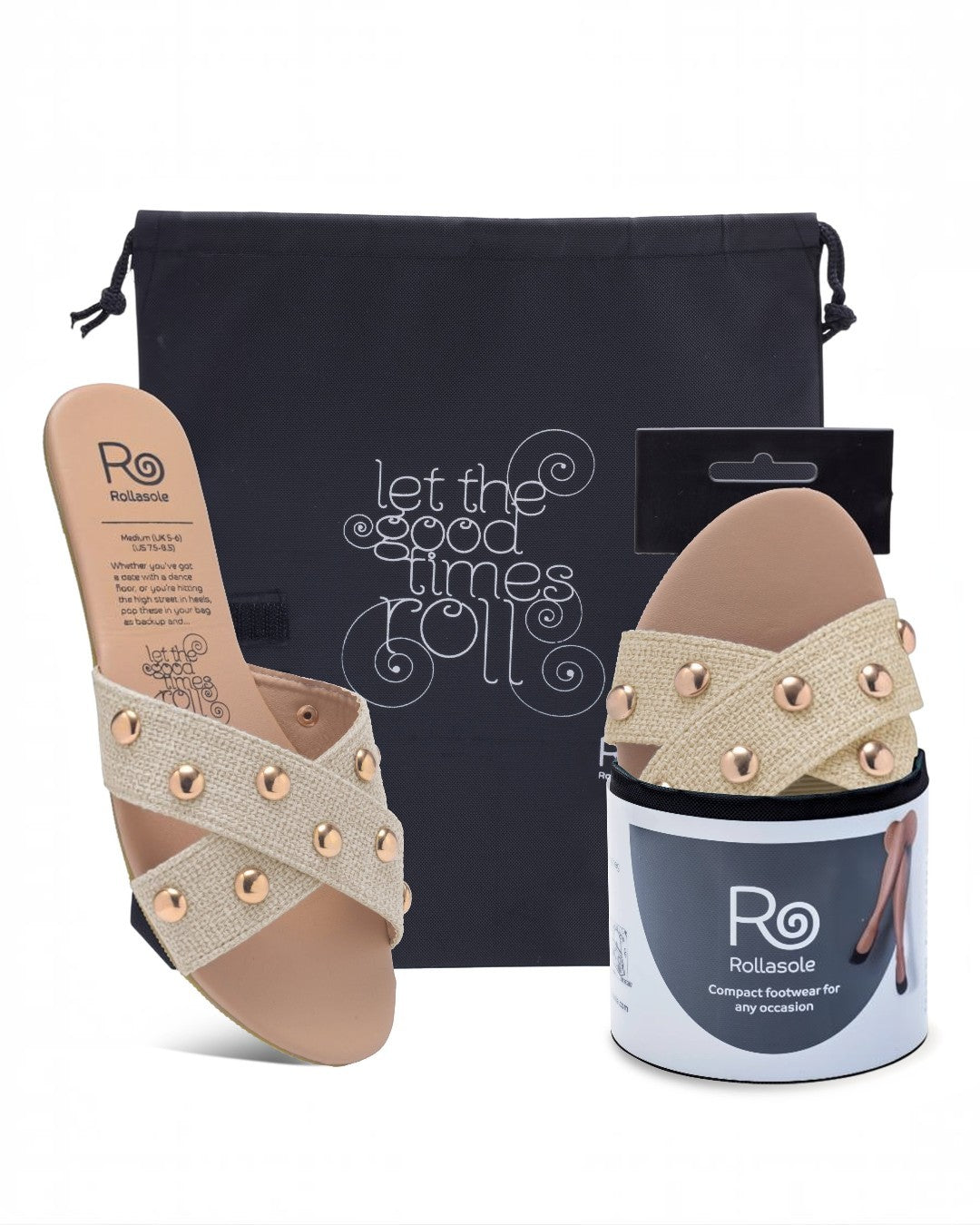 Pair of beige sandals with decorative straps, packaging, and a black bag on a white background.