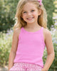 Young girl wearing a pink tank top and striped shorts standing outdoors with greenery in the background
