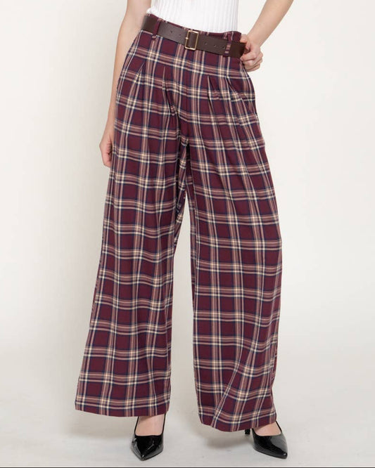 A woman modeling plus-size wide-leg plaid trousers with a brown belt, paired with a white ribbed sleeveless top, against a plain light background. A 'PLUS SIZE' label is visible in the top right corner.