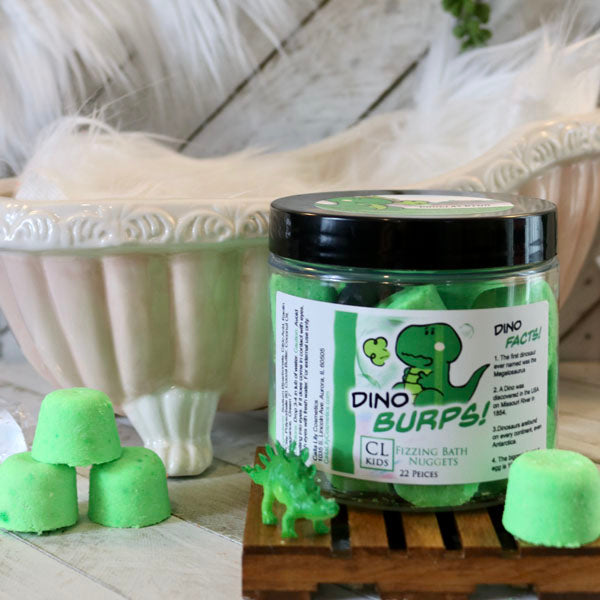 A container of gumdrop shaped green "dino burps" bath bombs with a tiny 3 bath bomb pyramid to its side