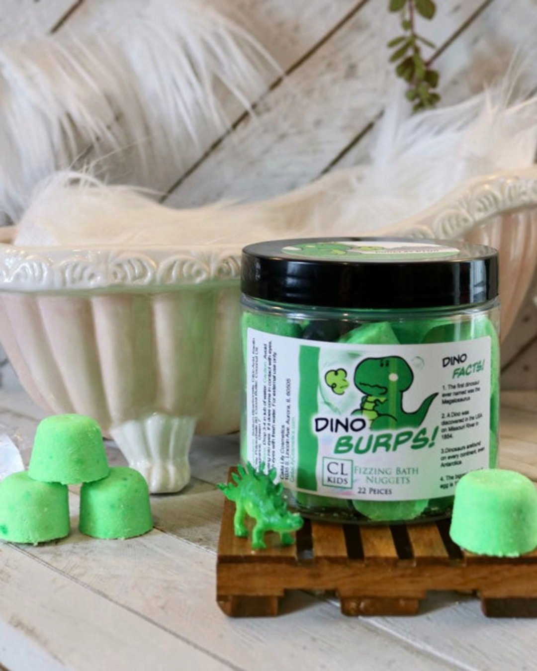 A container of gumdrop shaped green "dino burps" bath bombs with a tiny 3 bath bomb pyramid to its side
