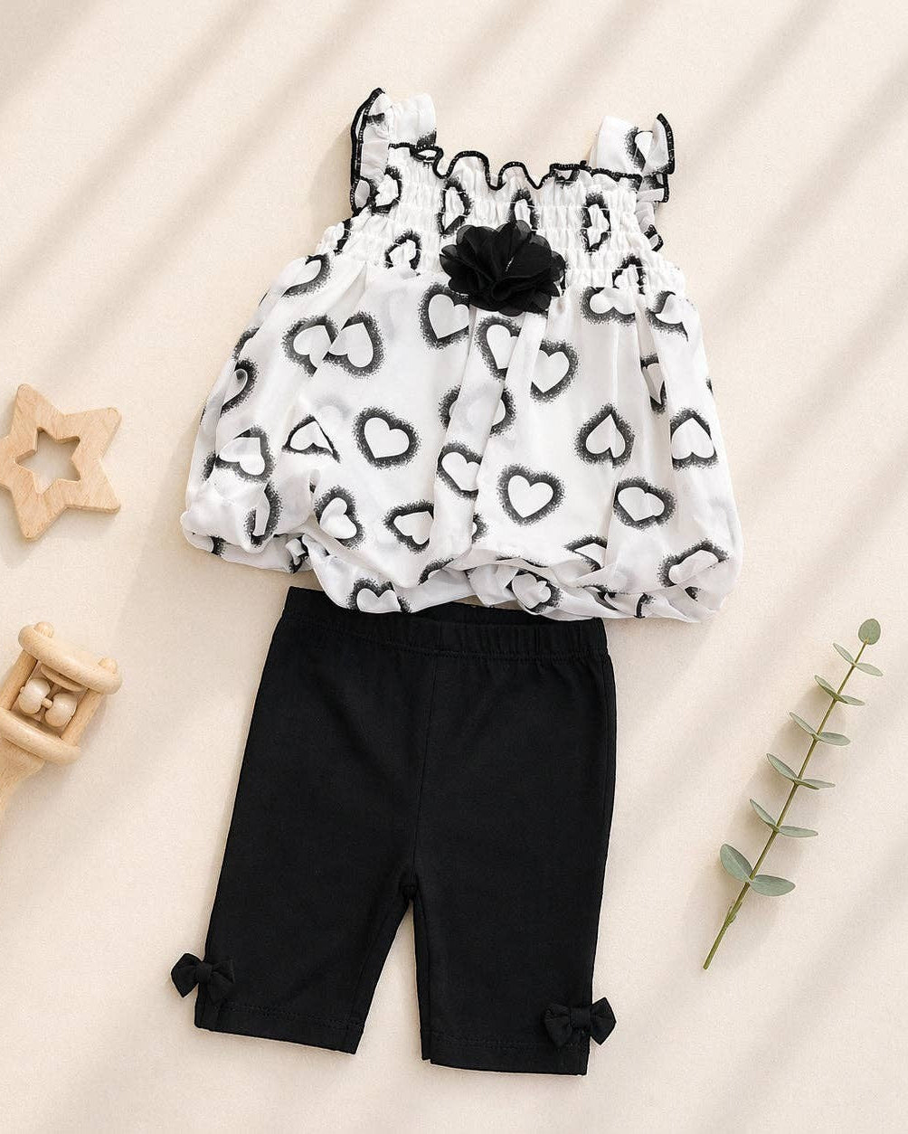 Children's outfit with black and white patterned top and black pants on a beige background
