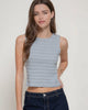 Woman wearing a striped tank top and jeans against a plain background