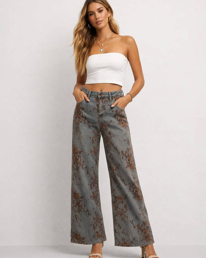 Woman wearing a white top and floral wide-leg pants on a plain background