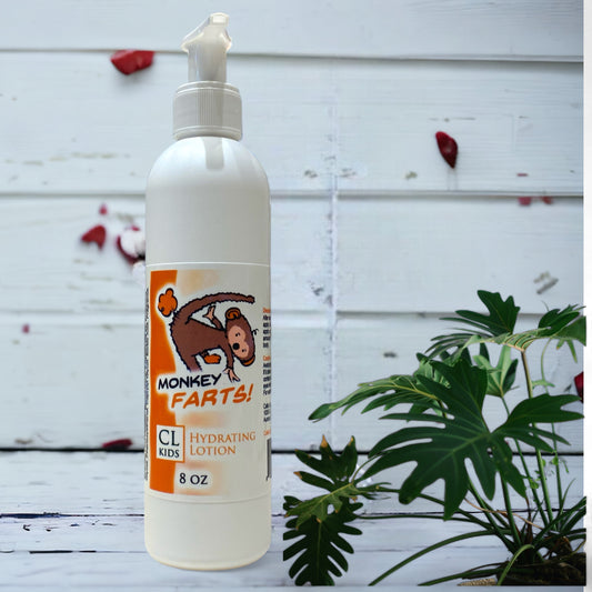 A white pump bottle of our monkey farts body lotion against a wood background