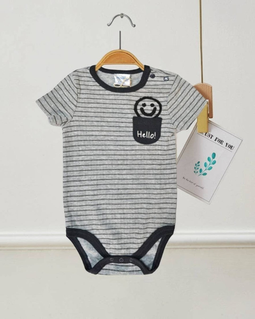 Gray striped baby onesie with a smiley face and 'Hello!' text on a hanger against a white background.