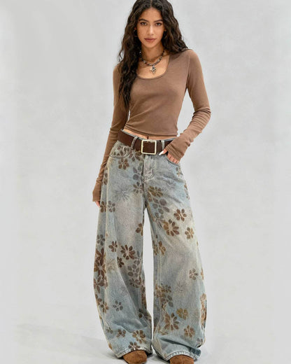 Woman wearing a brown long-sleeve top and floral wide-leg jeans on a white background