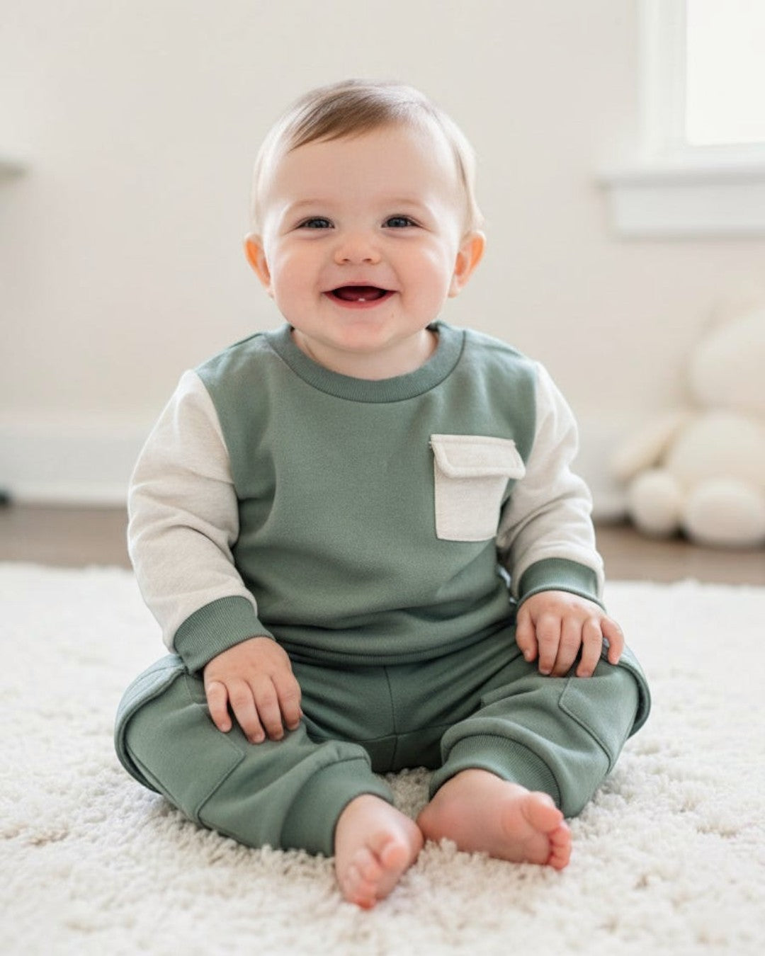Children's green outfit with a pocket on a hanger against a red background