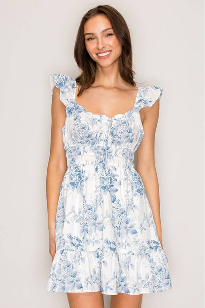 Woman wearing a white floral dress against a plain background
