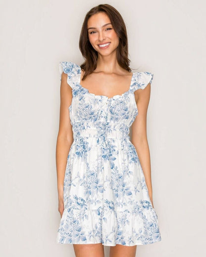 Woman wearing a white floral dress against a plain background