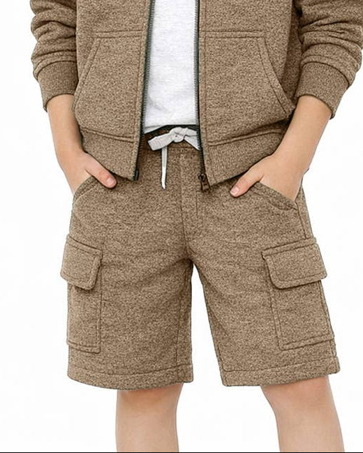 A young boy smiling and wearing a matching brown zip-up hooded sweatshirt and cargo shorts set over a white t-shirt, photographed against a solid white background.