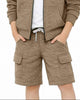 A young boy smiling and wearing a matching brown zip-up hooded sweatshirt and cargo shorts set over a white t-shirt, photographed against a solid white background.