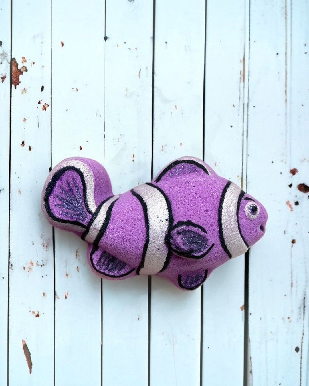 Calla Lily Cosmetics + CL kids purple clown fish bath bomb with glittery accents on a white wooden background