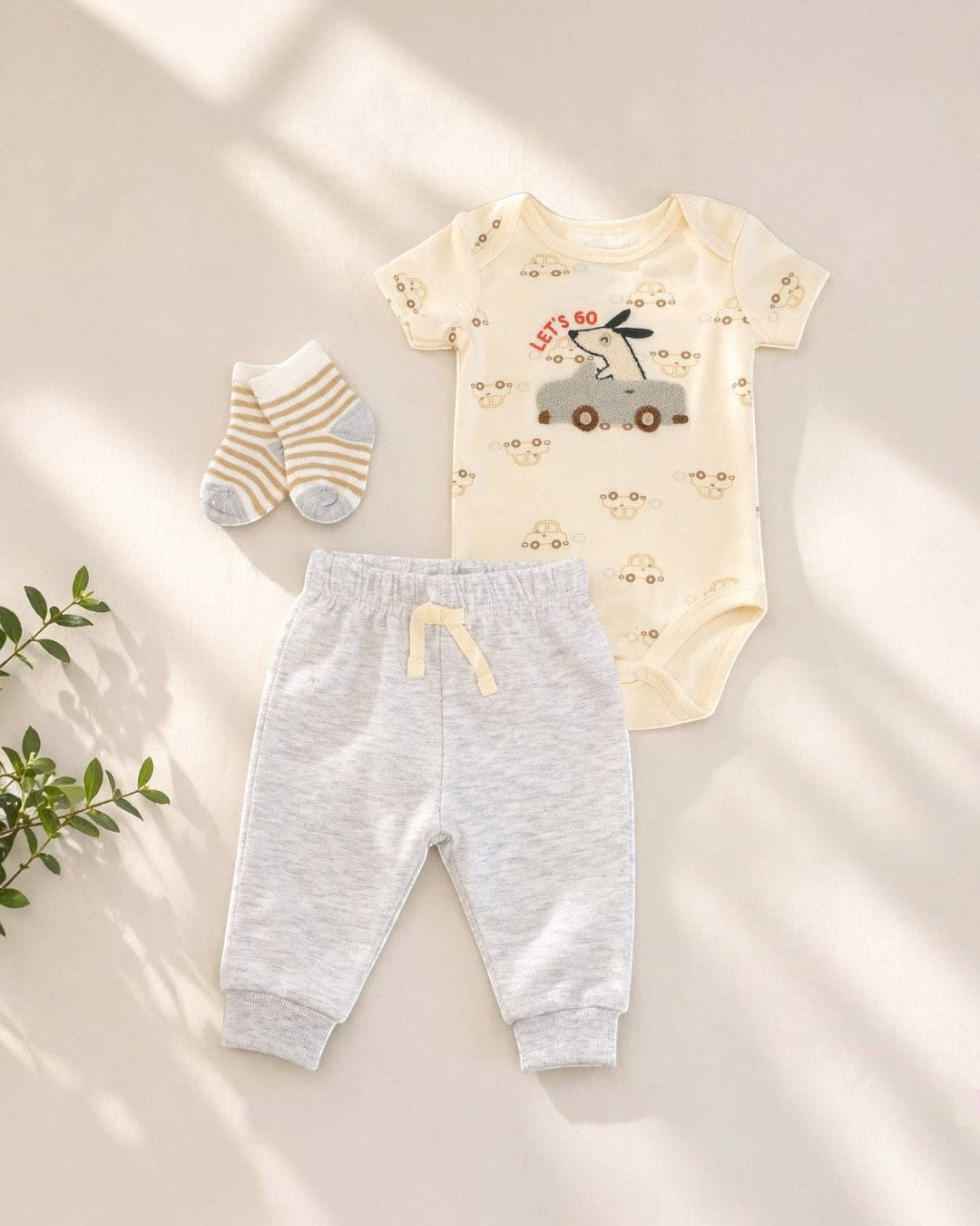 Baby outfit set with bodysuit, pants, and socks on a light background