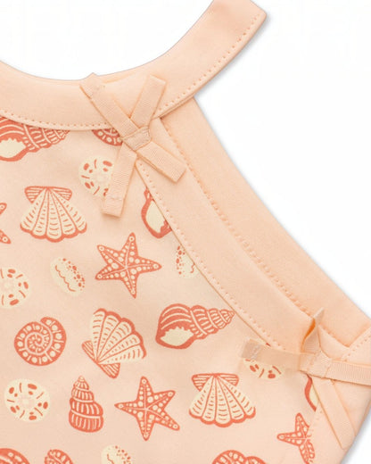 Baby outfit with shell pattern on a peach background