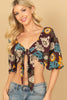 Woman wearing a colorful floral top and jeans on a beige background