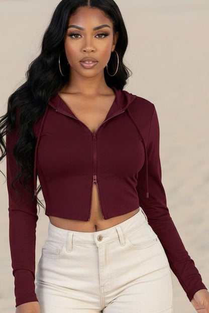 Woman wearing a burgundy long-sleeve crop top and black leather pants on a white background