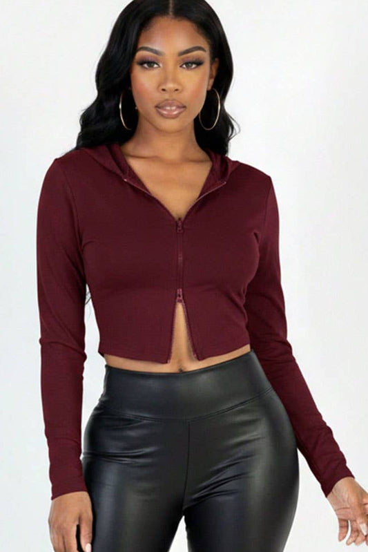 Woman wearing a burgundy long-sleeve crop top and black leather pants on a white background