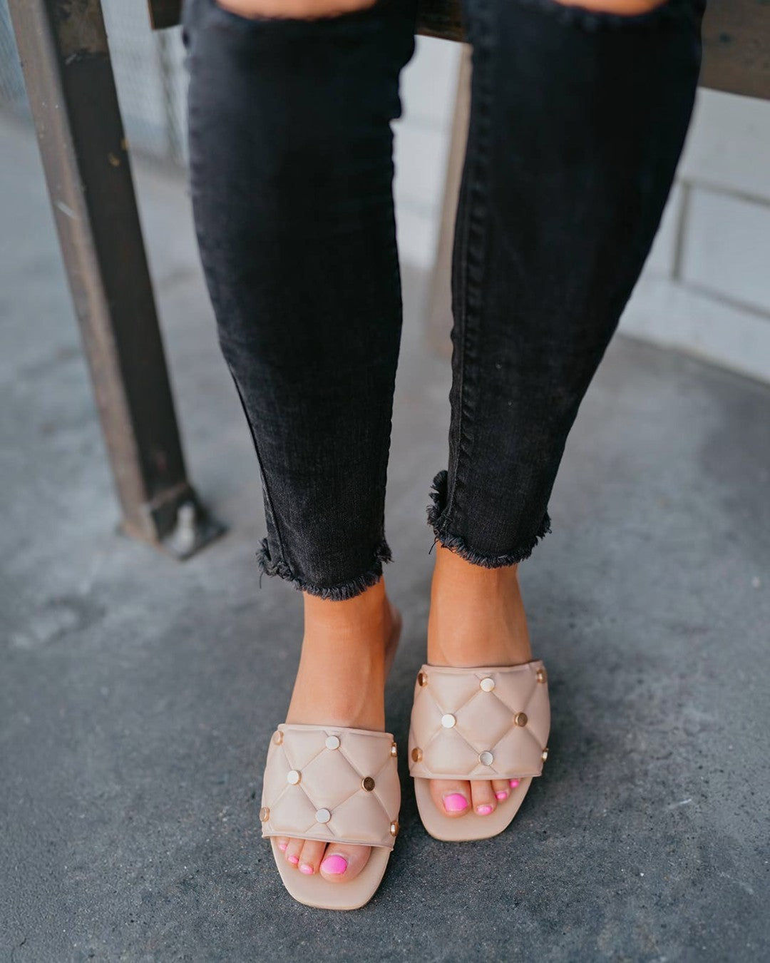 Close-up of feet wearing beige sandals with pearl embellishments on a blurred background