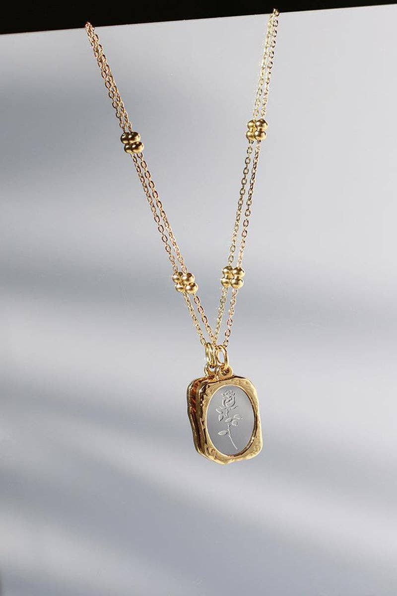 Gold necklace with a pendant on a light gray background
