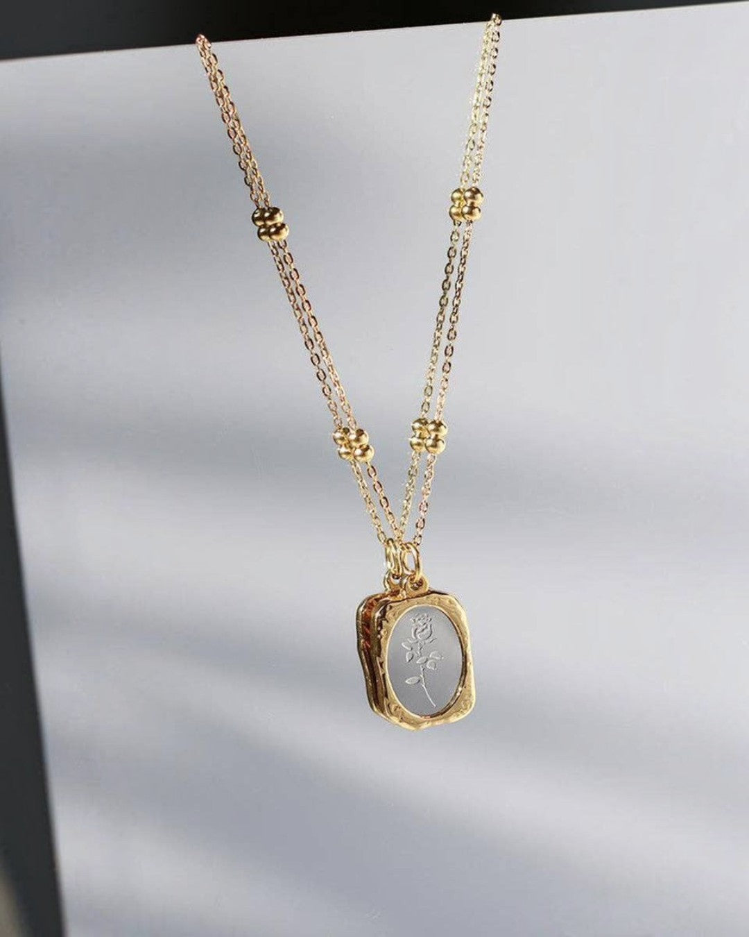 Gold necklace with a pendant on a light gray background