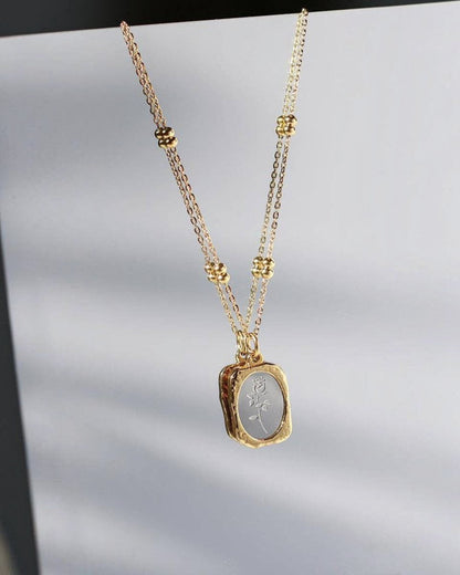 Gold necklace with a pendant on a light gray background