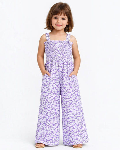 Young girl wearing a purple floral jumpsuit on a white background