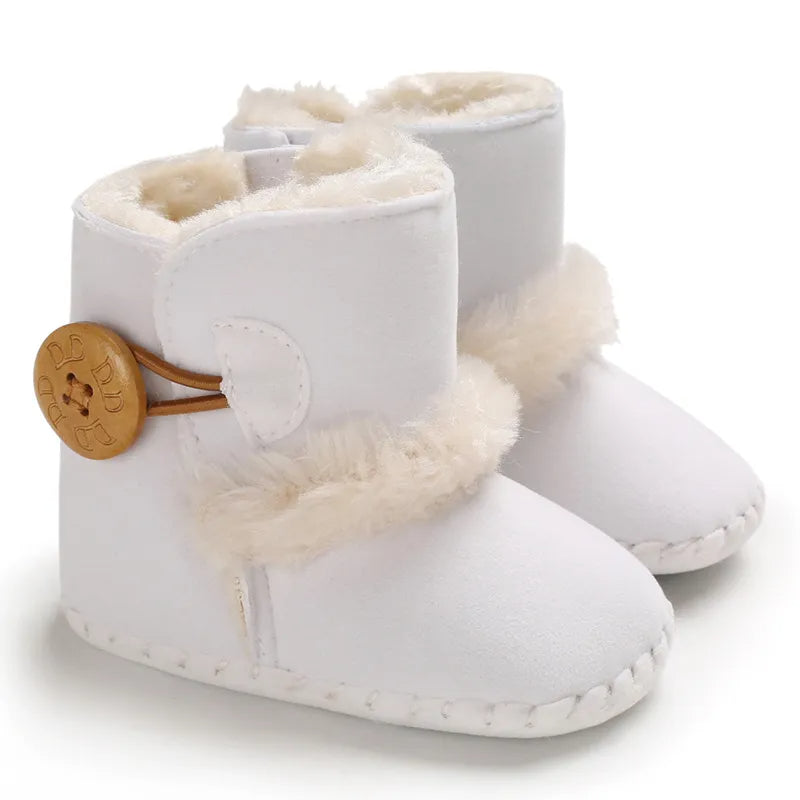 White baby boots with fur trim and a brown button on a white background