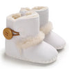 White baby boots with fur trim and a brown button on a white background